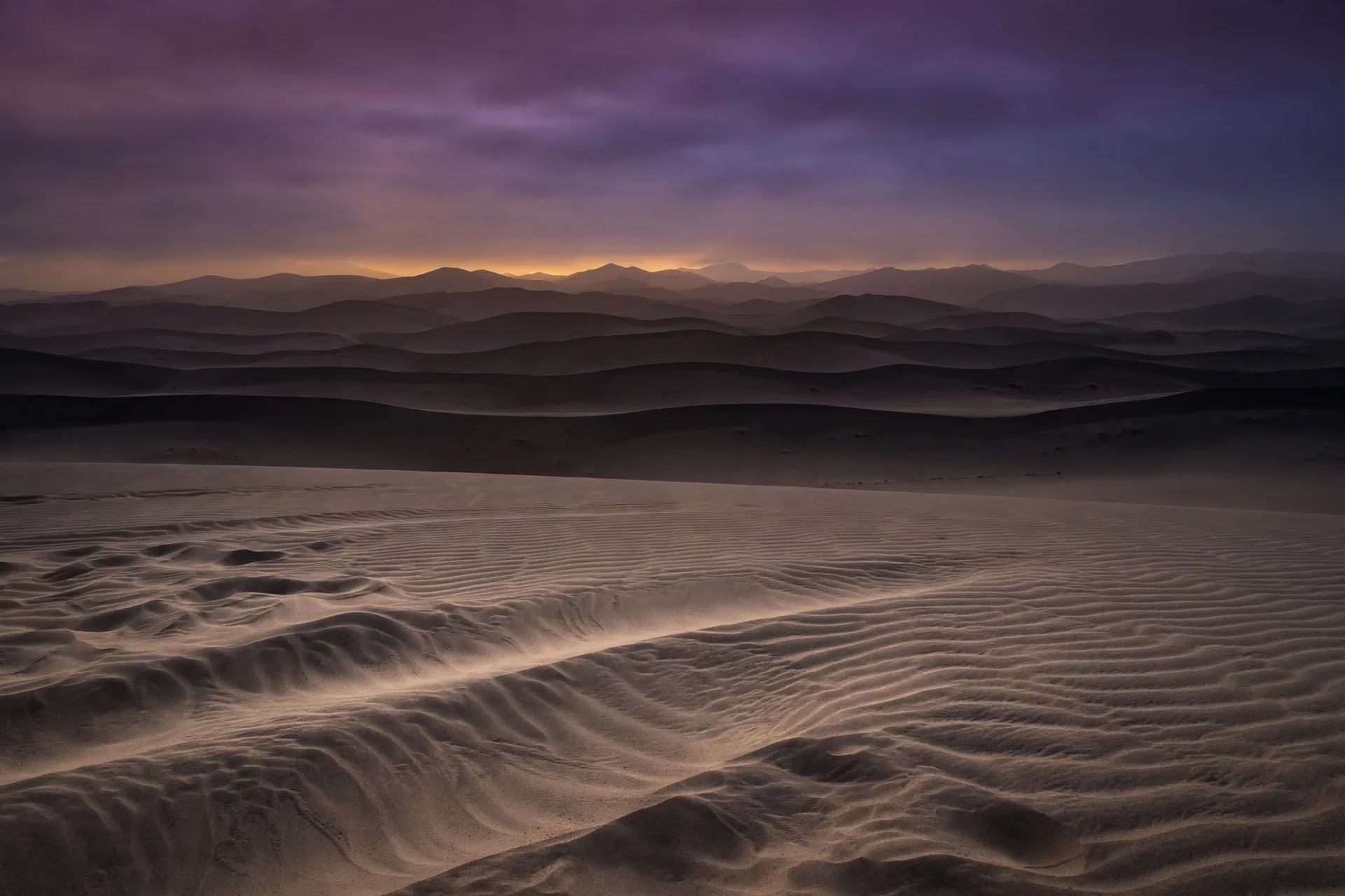 Desert dune ridges under a plum-violet dusk sky